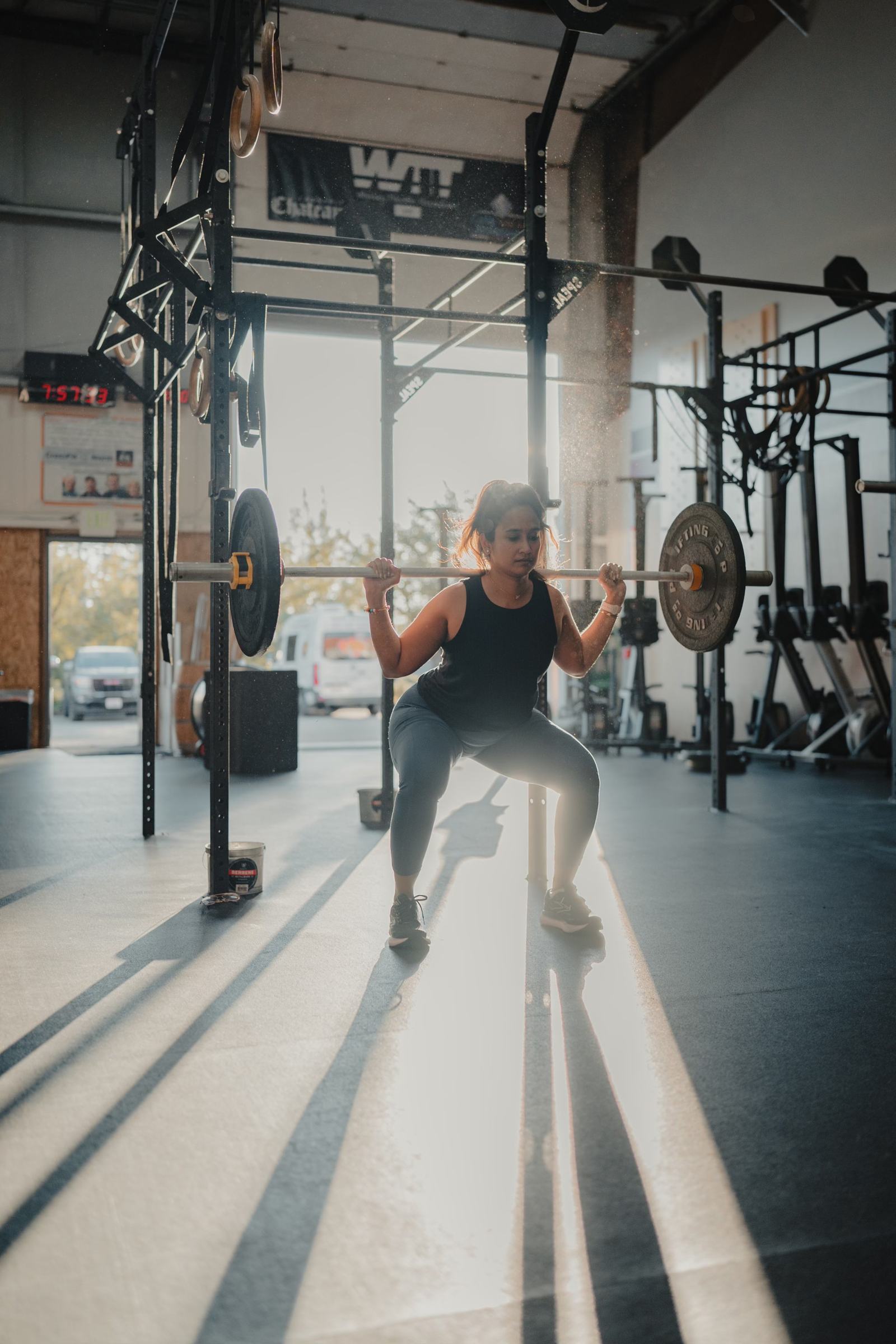 Real WeSweat community member mid-lift, backlit gym
